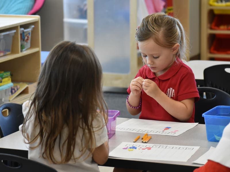 Preschool students in school uniform at their desk coloring pictures and drawing