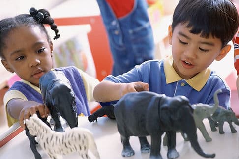 Two children playing with plastic animals