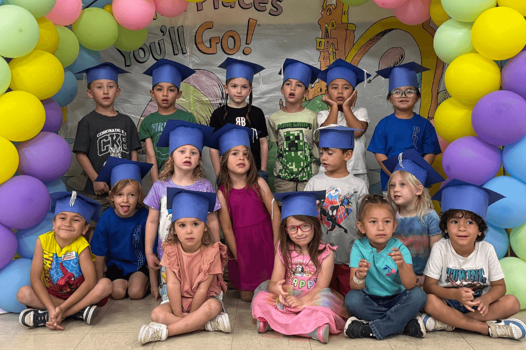 A group of children wearing graduation caps pose for a photo.