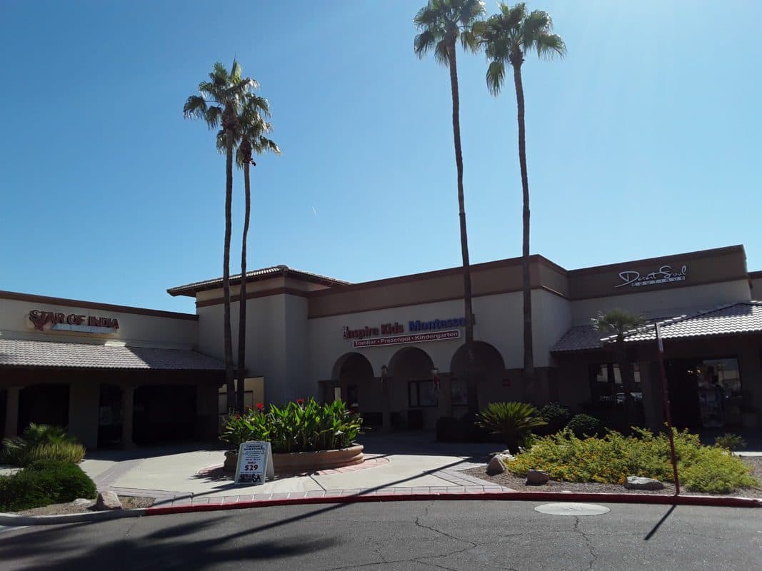 A storefront with palm trees and "Inspire Kids Montessori".