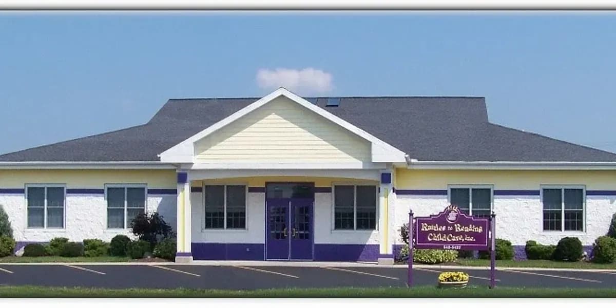 Single-story building with white siding, blue roof, and a purple sign in front