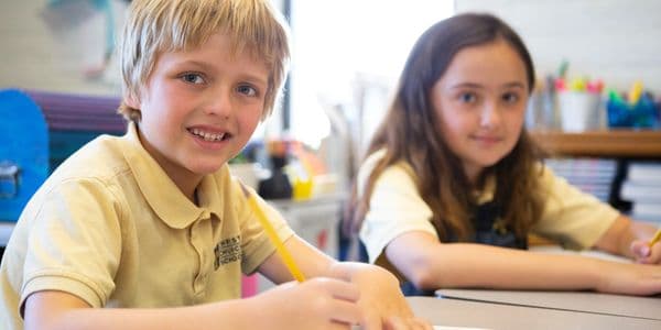 Two students working at their desks in a classroom.