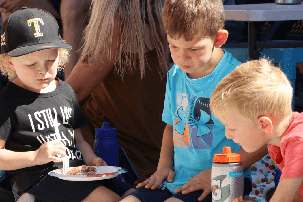 Children gather around a table, possibly eating or crafting.