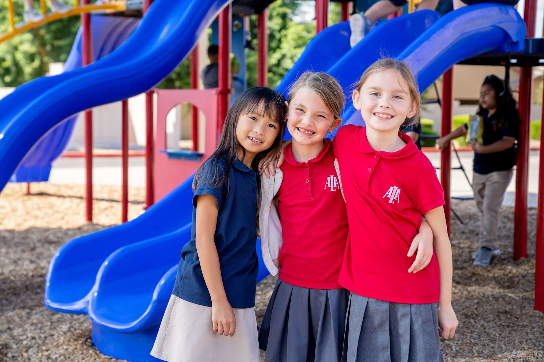Three Little Leaders students posing with each other for a photo on the playground