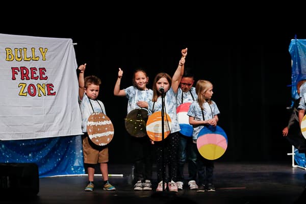 Opera performers backed by sign, Bully Free Zone.