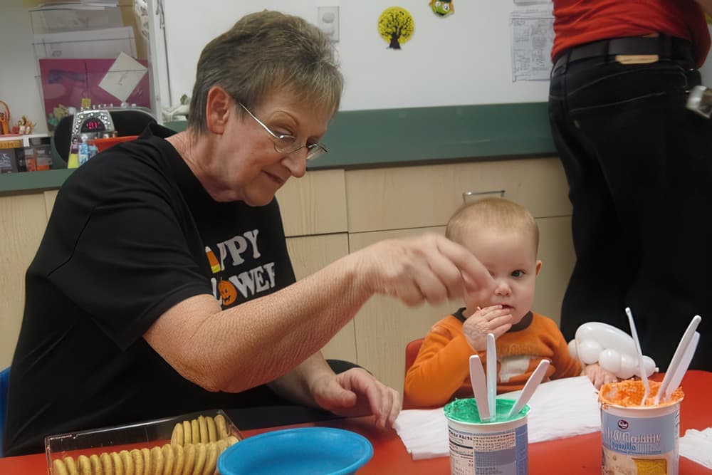 Teacher and toddler enjoy colorful snack activity.
