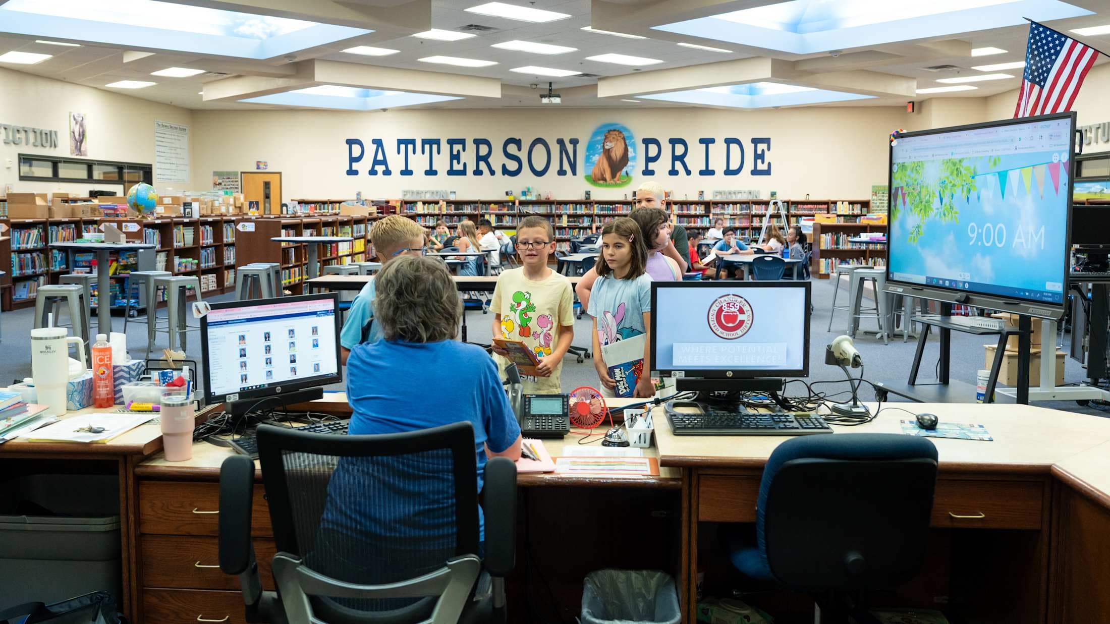 A wide angle of the elementary school library. On the wall it says Patterson Pride with a lion between the words.