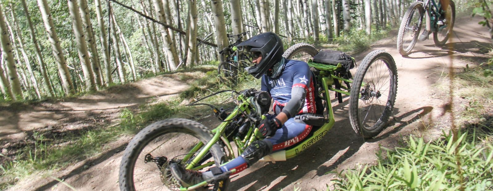 Man riding down a trail on a hand cycle.