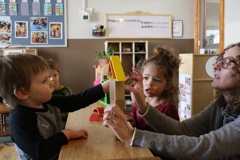 Children and an educator together in a classroom setting.