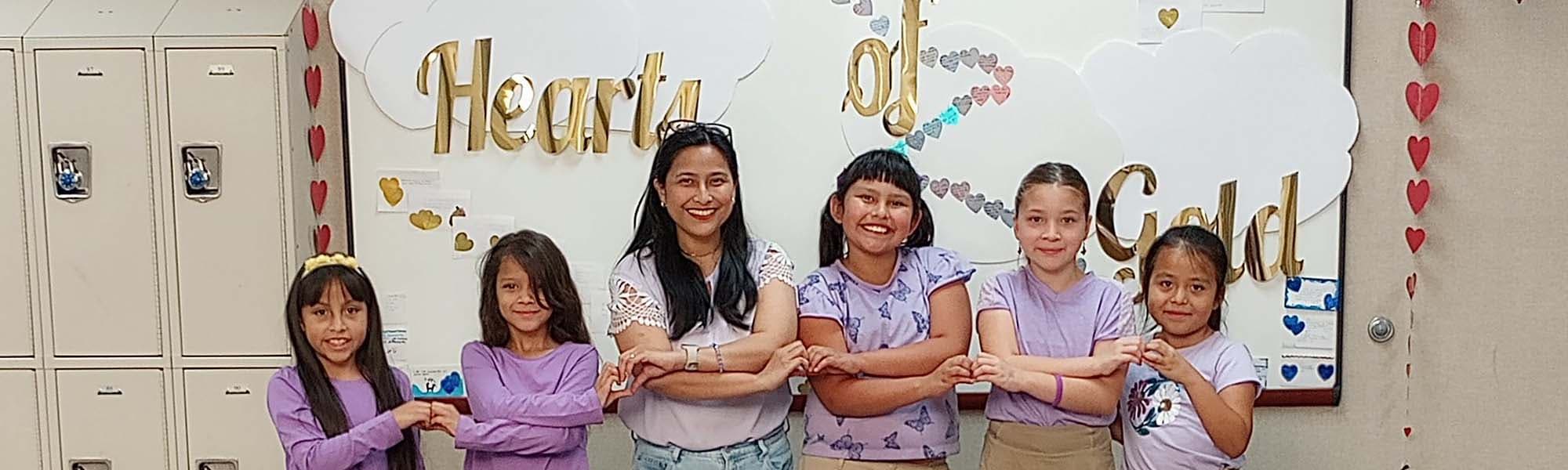 Students in front of hearts of gold poster