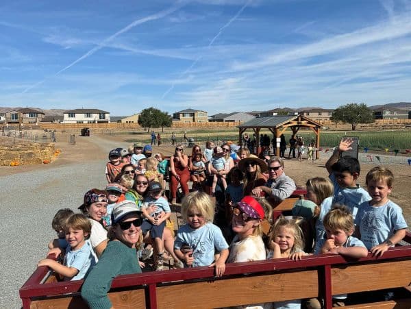 Group of kids and adults on a hayride on a sunny day.