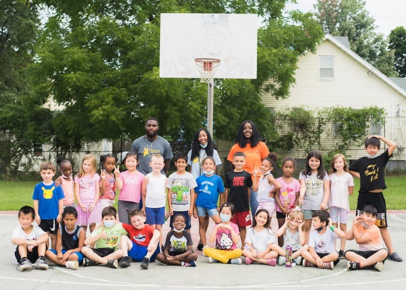 Diverse group of elementary school students grouped with their teachers on a basketball court outside at Stars Atlantic Afterschool program