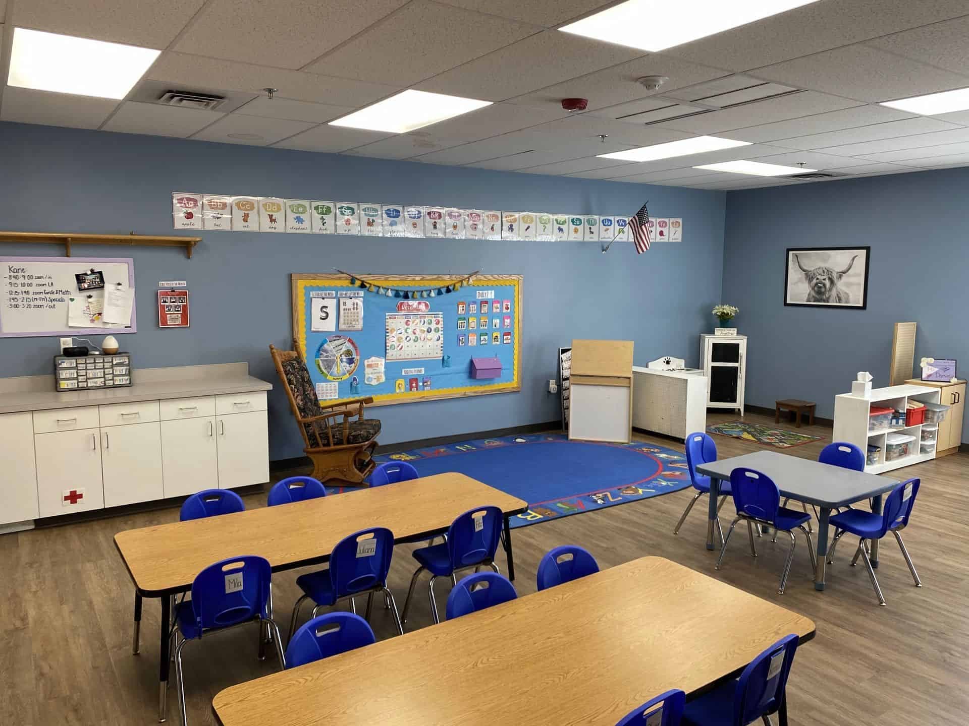 Bright preschool classroom with colorful educational posters and furniture.