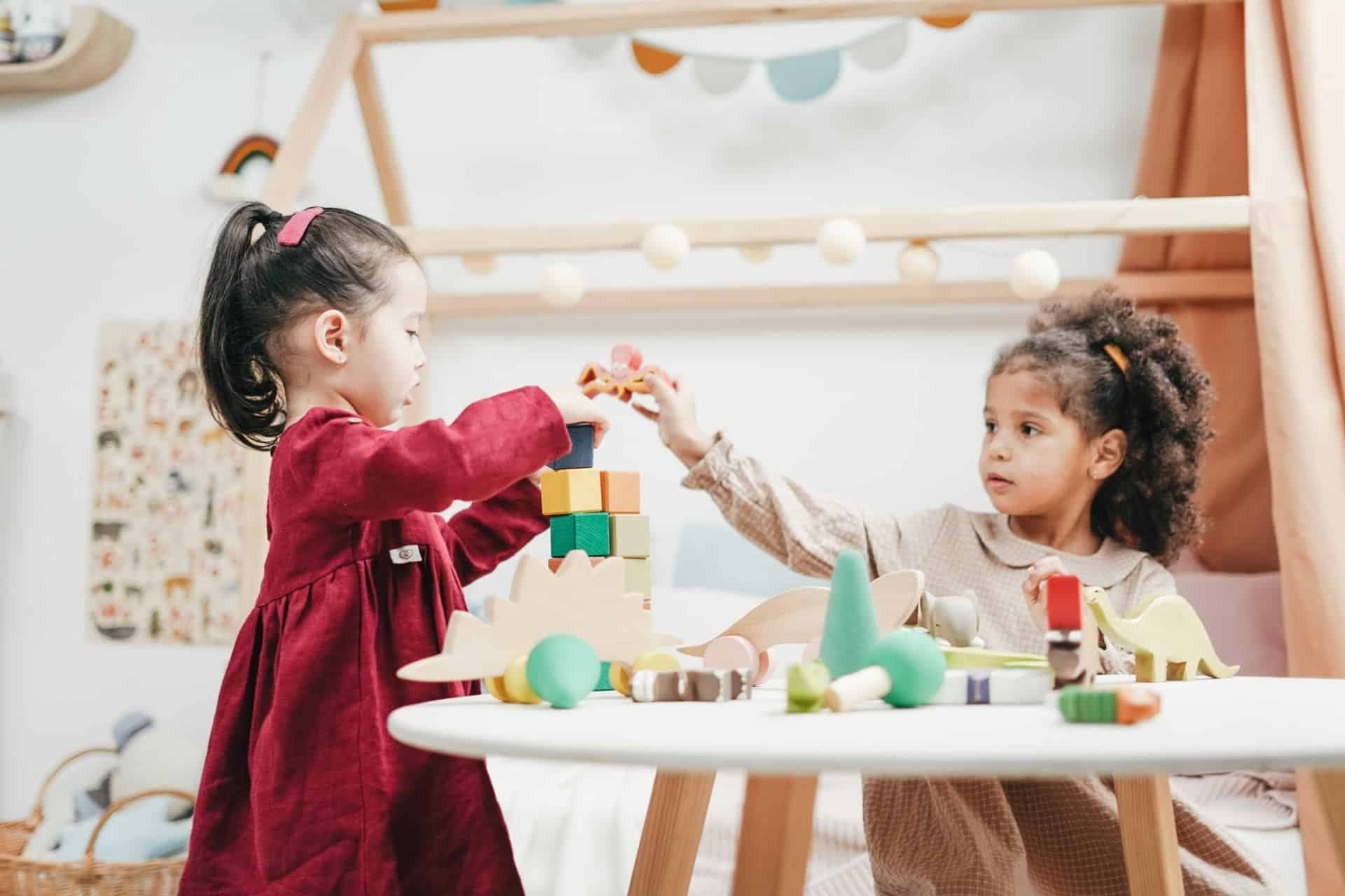 Children playing with wooden blocks and toys at a table.