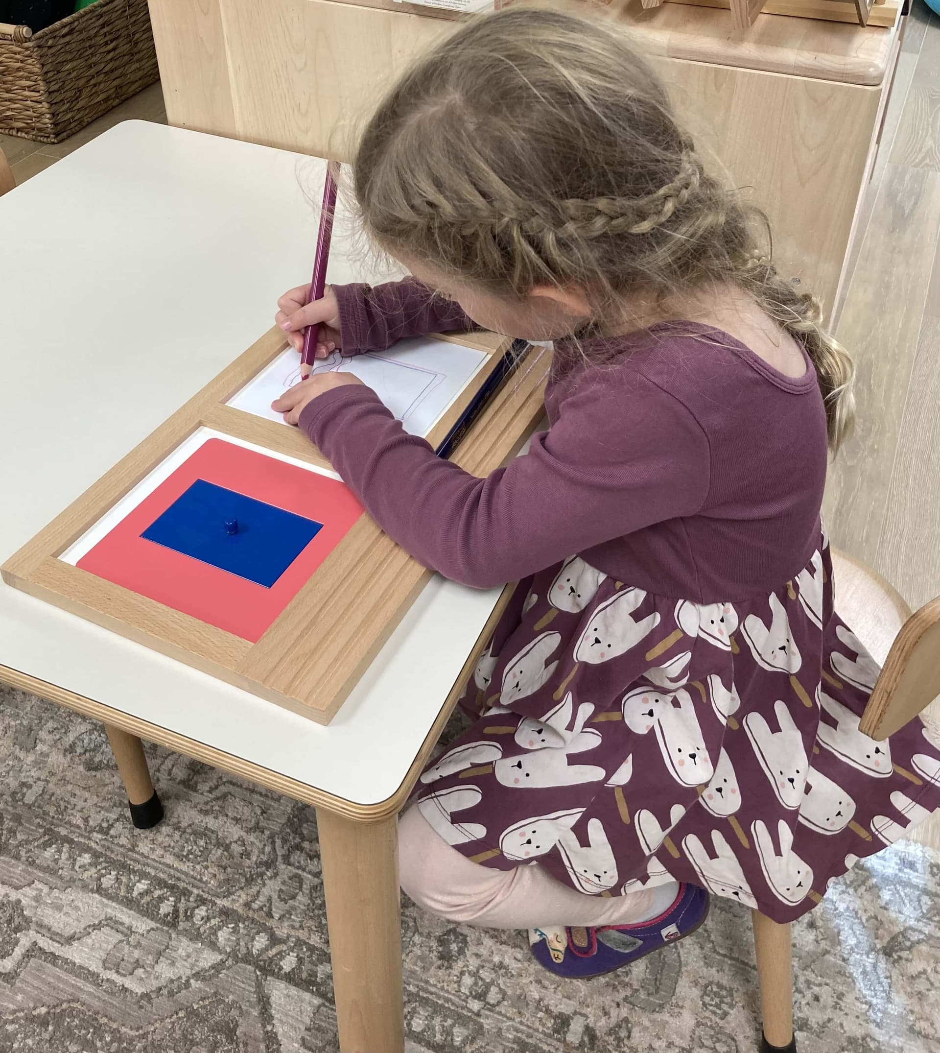 A preschooler working with Montessori metal insets in the Primary classroom at Beacon Montessori in Weston, MA