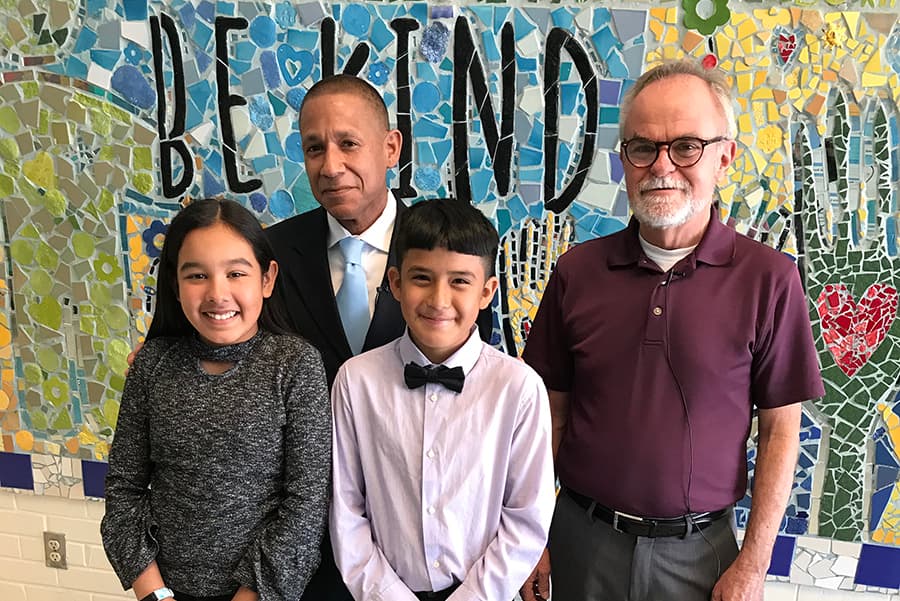 Dr. Trujillo, a TUSD staff member and two students stand in front of a Be Kind mural