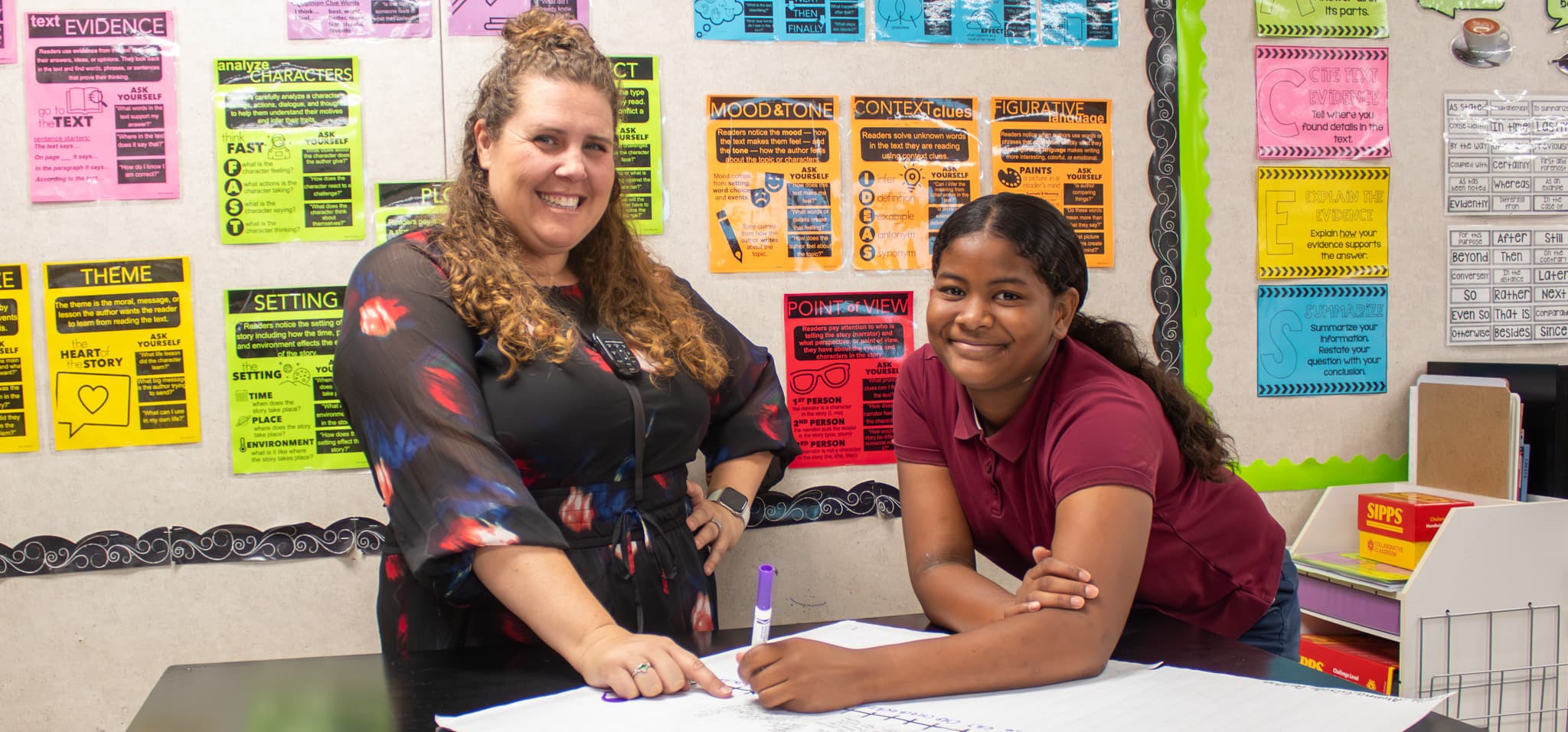 Teacher and student standing at a table smiling.