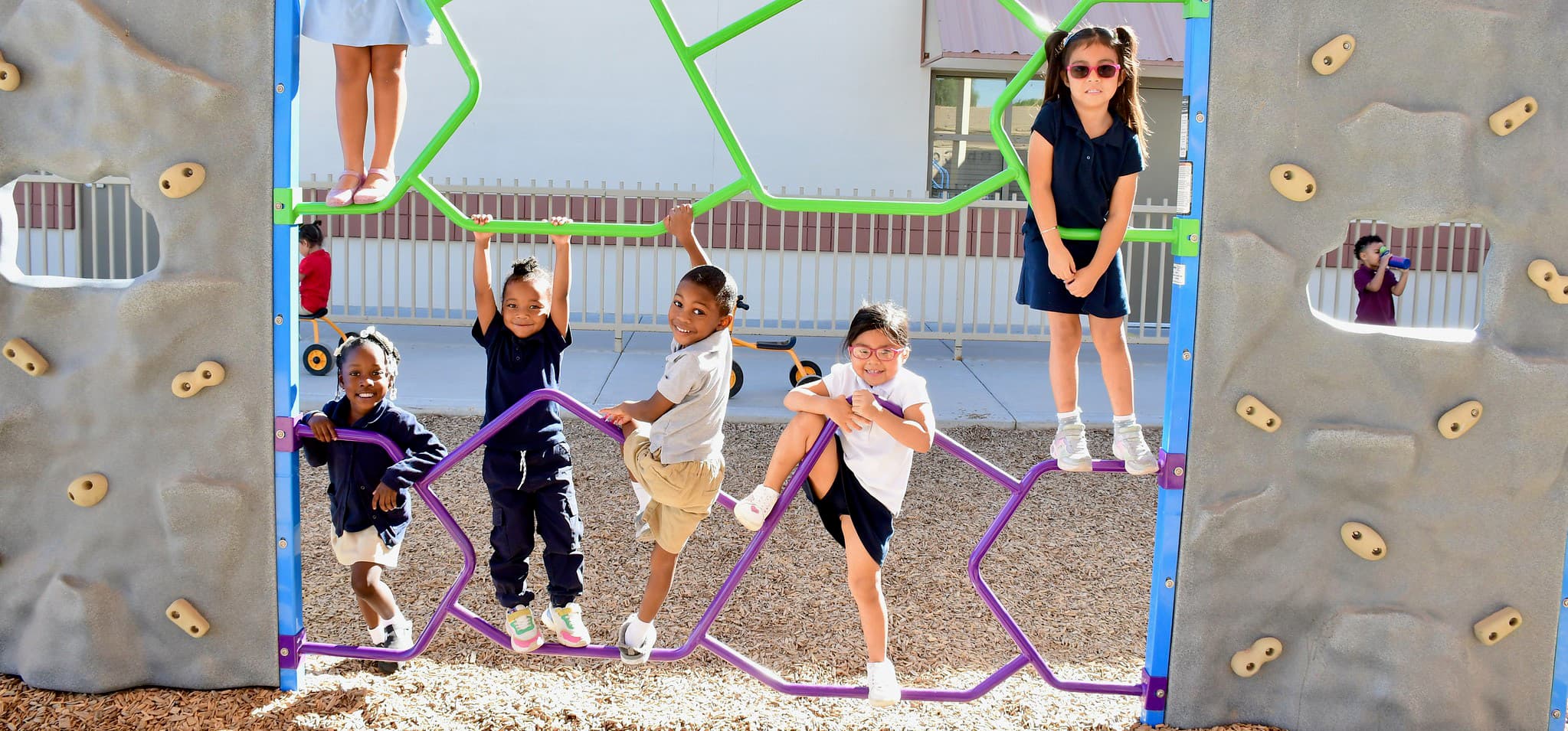Student smiling at the camera and climbing on the playground